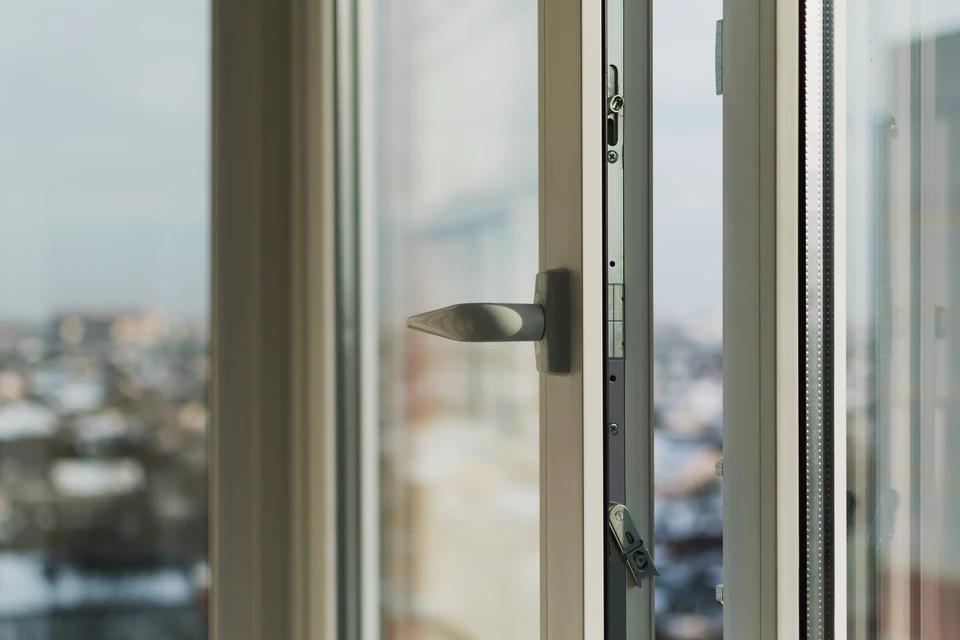 Gros plan d'un artisan en tenue professionnelle effectuant la pose d'une fen&ecirc;tre isolante en aluminium (menuiserie ext&eacute;rieure) dans le cadre d'une baie vitr&eacute;e d'une maison en r&eacute;novation. L'artisan est concentr&eacute; sur son travail, manipulant la fen&ecirc;tre avec ses outils professionnels (&eacute;querre, tournevis, etc.). L'arri&egrave;re-plan montre le cadre de la maison et la lumi&egrave;re naturelle p&eacute;n&eacute;trant par la nouvelle menuiserie. La sc&egrave;ne d&eacute;montre clairement un travail de menuiserie ext&eacute;rieure RGE dans un contexte r&eacute;sidentiel de r&eacute;novation.
