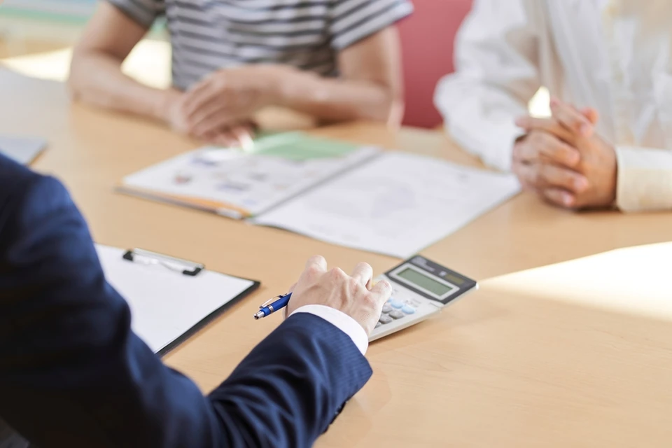 R&eacute;union d'affaires autour d'une table en bois avec plusieurs personnes analysant des documents contractuels
