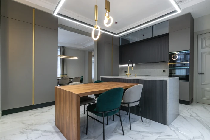 Homme mature en salopette jaune et pull gris travaillant au plafond, bras levés tenant des outils de rénovation