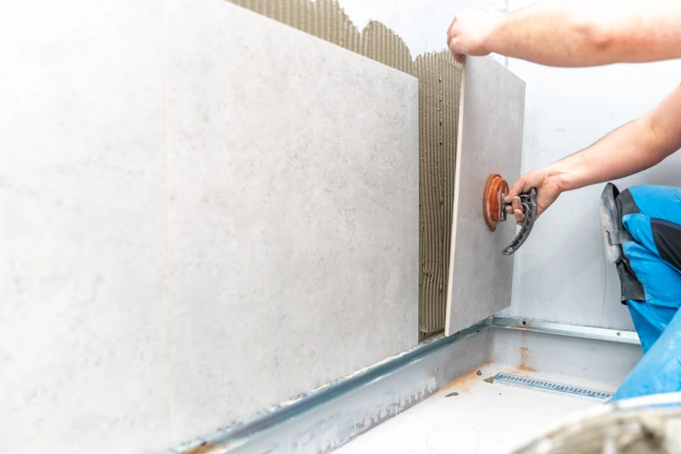 Artisan carreleur professionnel appliquant du joint silicone dans l'angle d'une salle de bain moderne