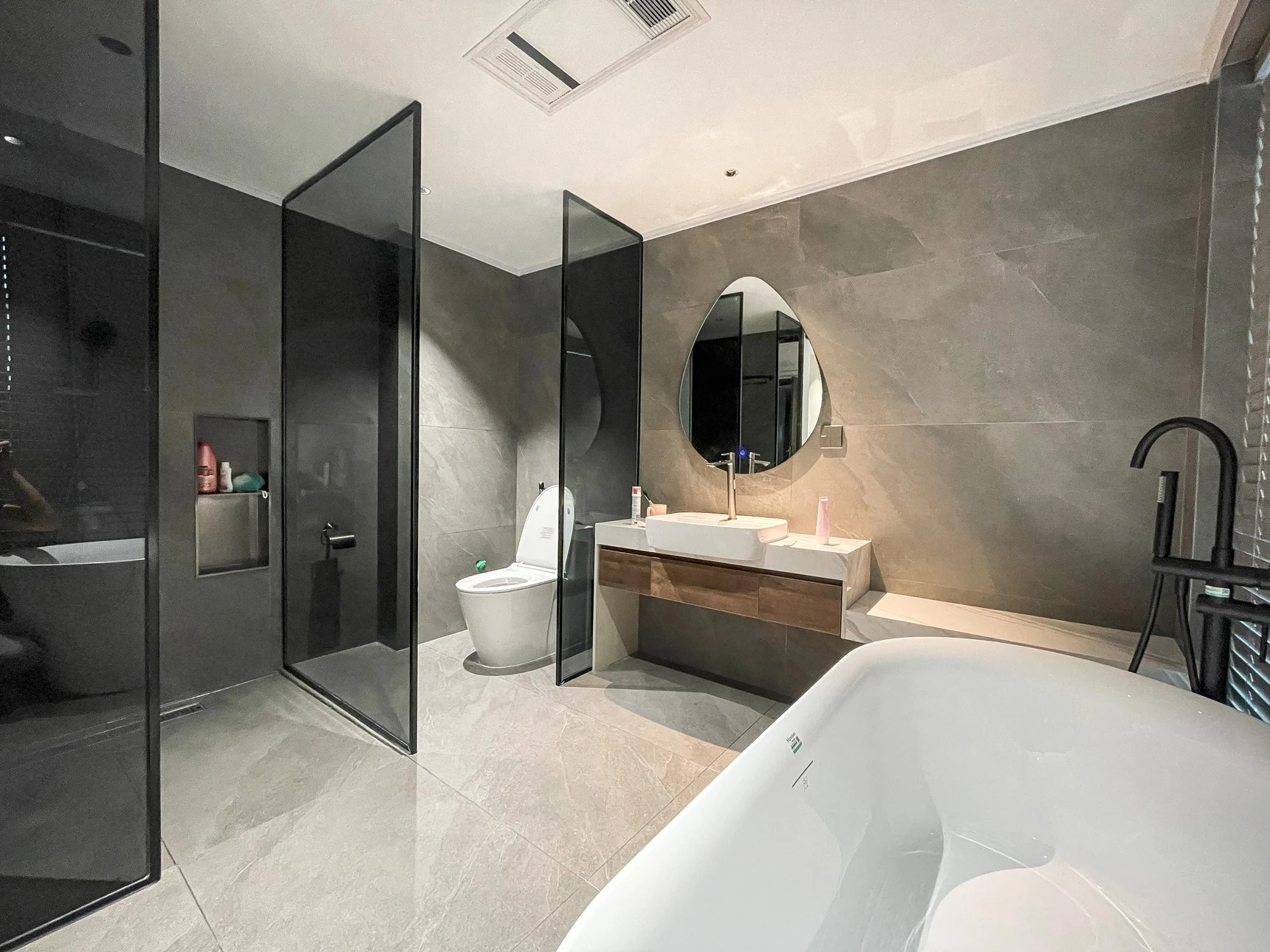 Salle de bain moderne avec douche à l'italienne vitrée, WC suspendu, vasque sur plan en granit avec robinetterie contemporaine