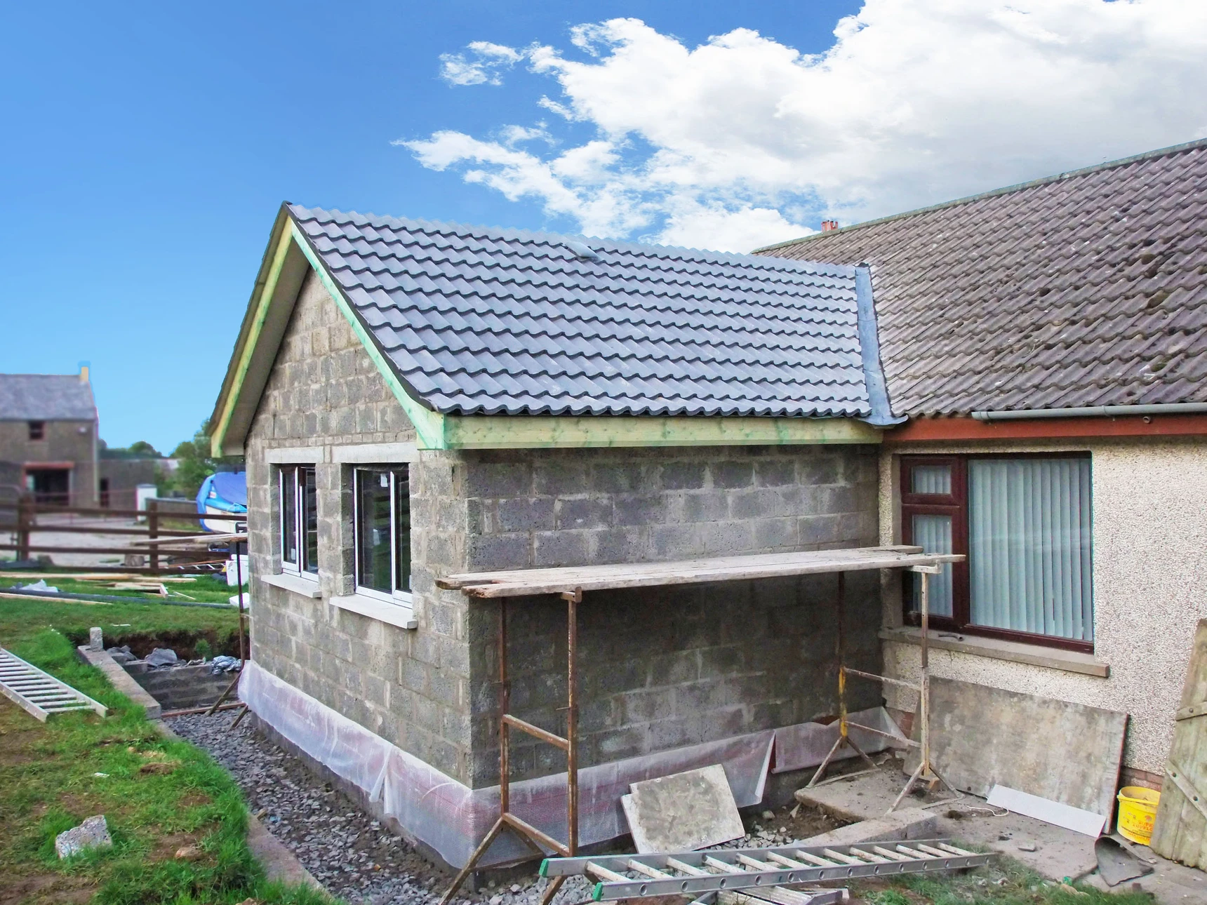 Chantier de construction résidentielle en cours avec maison à deux niveaux en béton armé et maçonnerie de briques